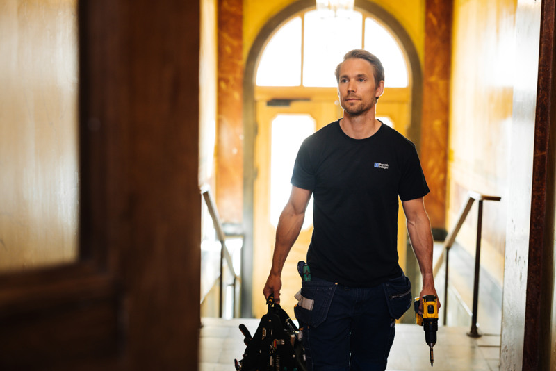 En man som går i en korridor med ett verktyg i handen.