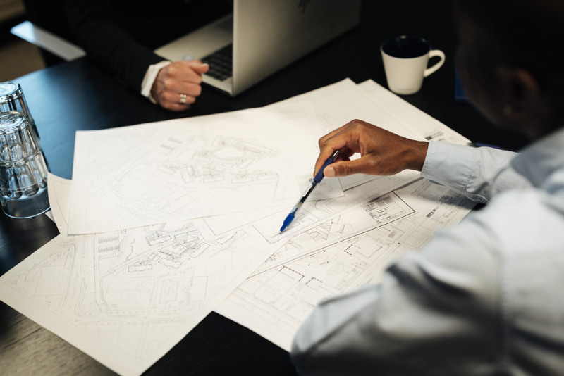 Två personer sitter vid ett bord med papper och en bärbar dator.