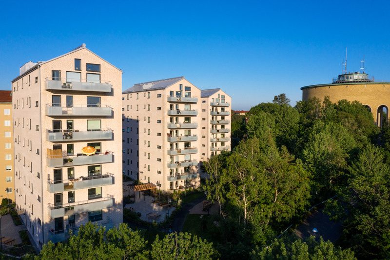 Bild på Bostadsbolagets fastigheter vid Doktor Sven Johanssons Backe, i en solig och grönskande miljö. 