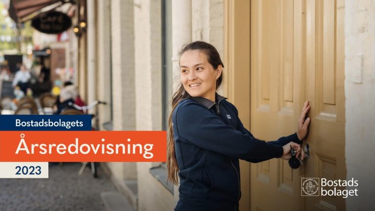 En leende kvinna står utanför en byggnad och låser upp en dörr. 