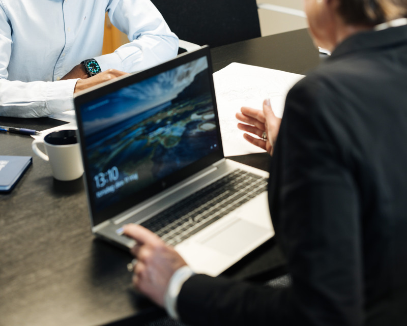 En man och en kvinna sitter vid ett bord med en bärbar dator.