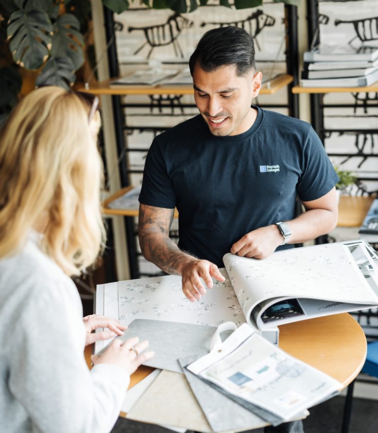 En man och en kvinna står vid ett bord och kollar på tapeter.