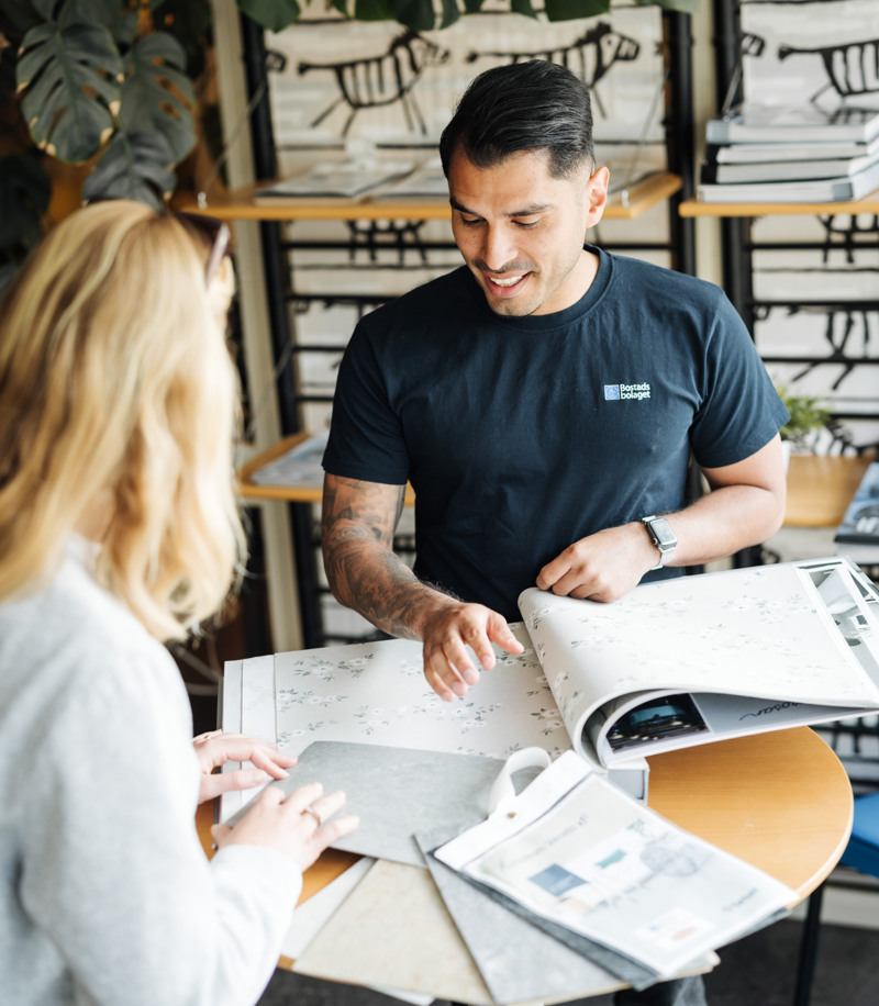 En man och en kvinna står vid ett bord och kollar på tapeter.