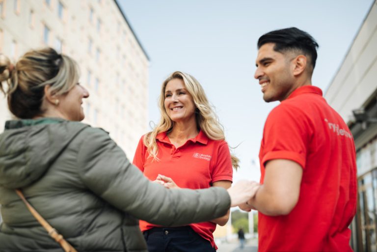 En kvinna pratar med en man och en kvinna i röda tröjor.