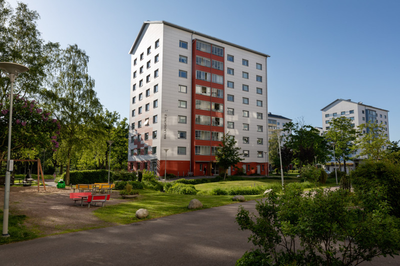 En röd och vit byggnad som ligger intill en grönskande park.