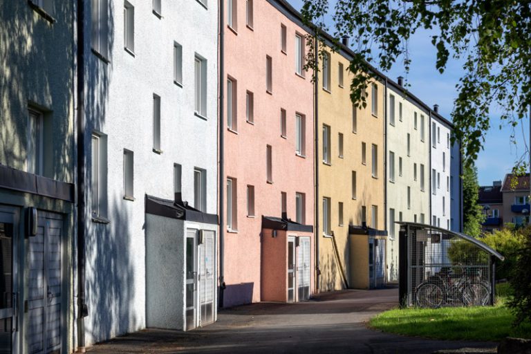 En rad flerfärgade hyreshus på en solig dag.