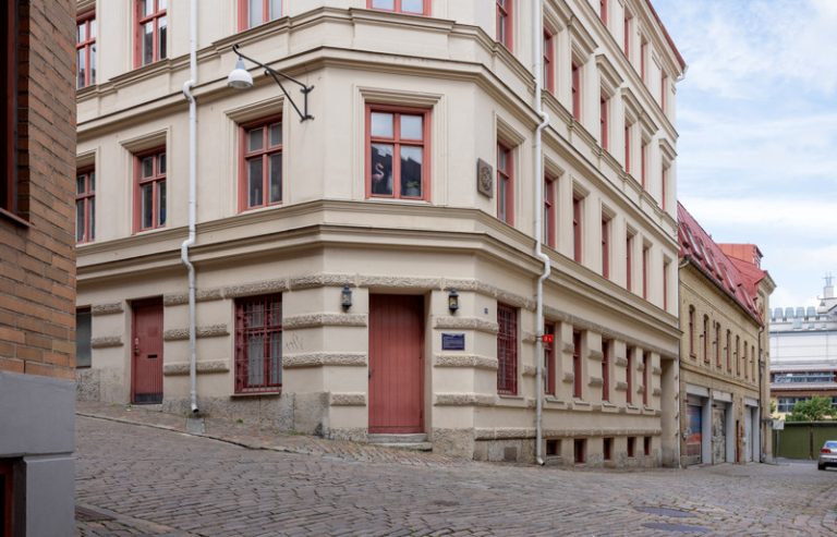 En gammal byggnad med en röd dörr på en kullerstensgata.