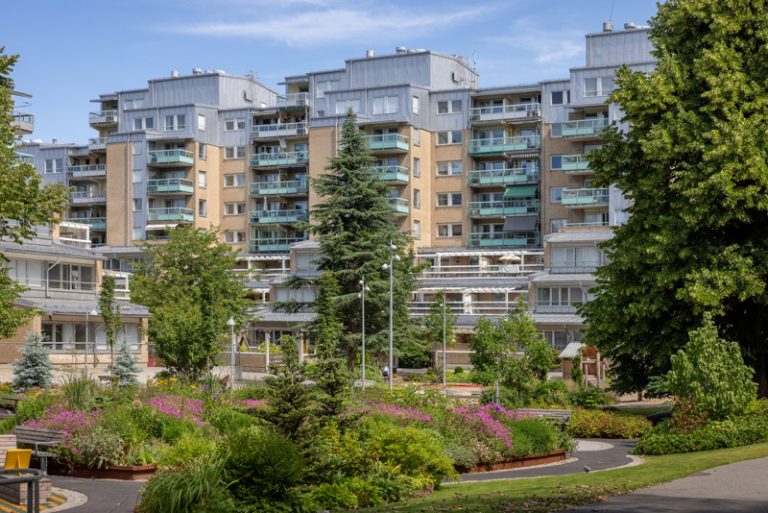 Ett stort hyreshus med en grönskande innergård.