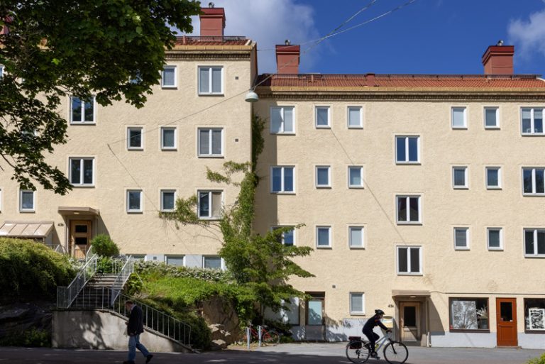 En man cyklar förbi en ljusgul byggnad.