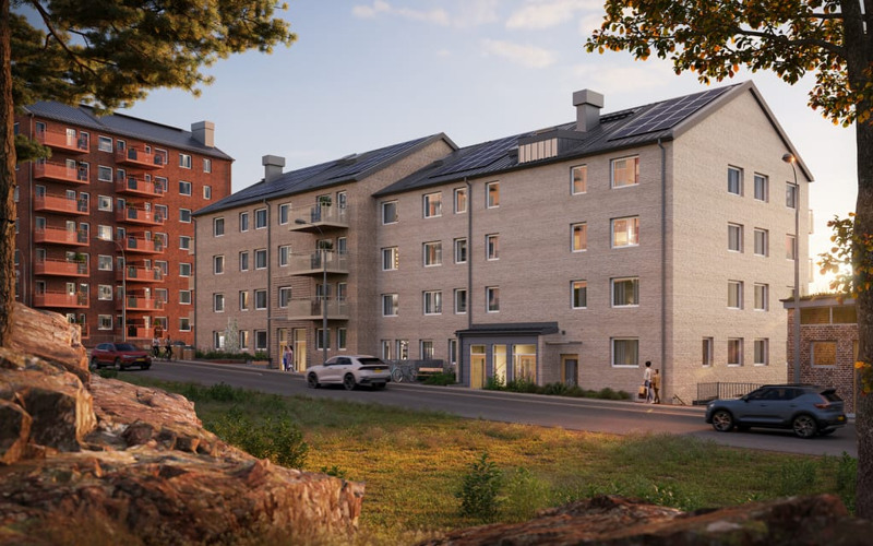 En visualiseringsbild av ett beige hyreshus. I förgrunden syns bilar, grönska och en trottoar. 