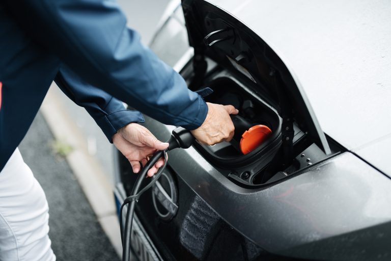 En person kopplar in en laddare i en elbil. 