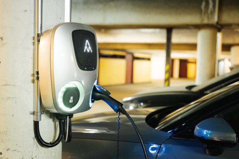 En elbil som är ansluten till en laddningsstation i ett parkeringsgarage.
