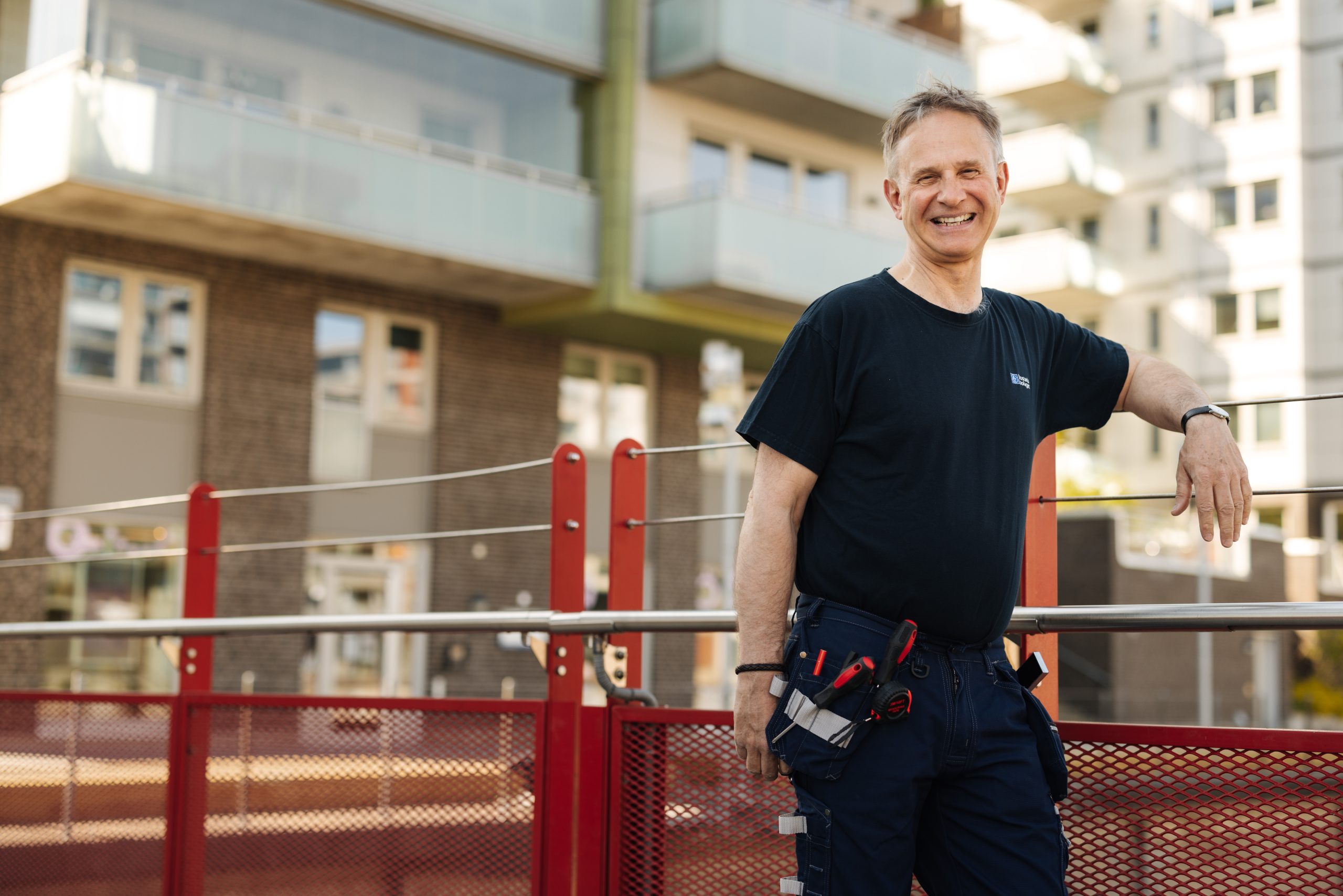 En man står bredvid ett staket framför en byggnad.