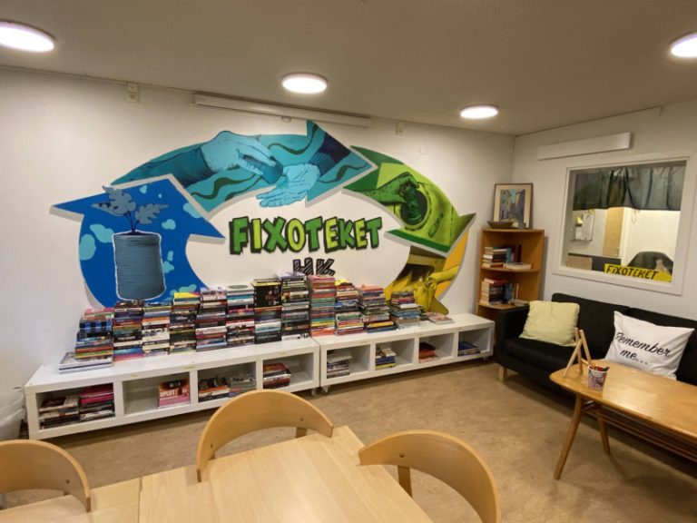 Ett rum med bord, stolar och en skylt på väggen.