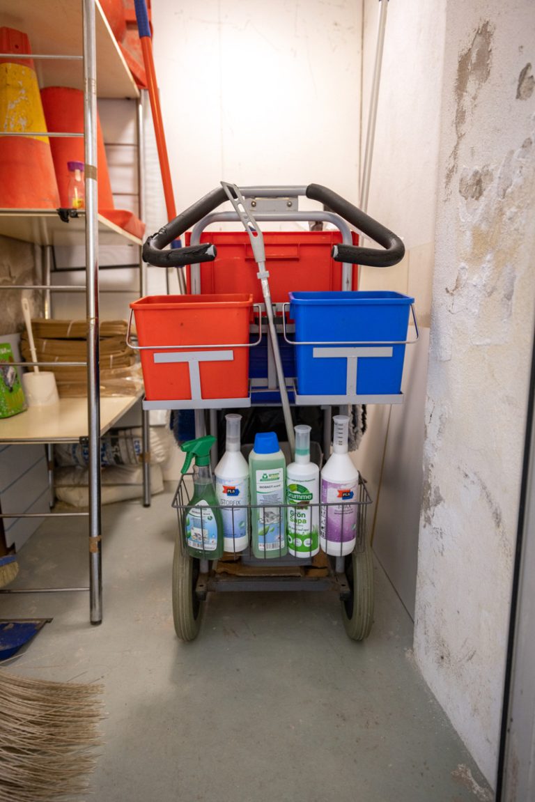En städvagn fylld med rengöringsmedel i ett rum.