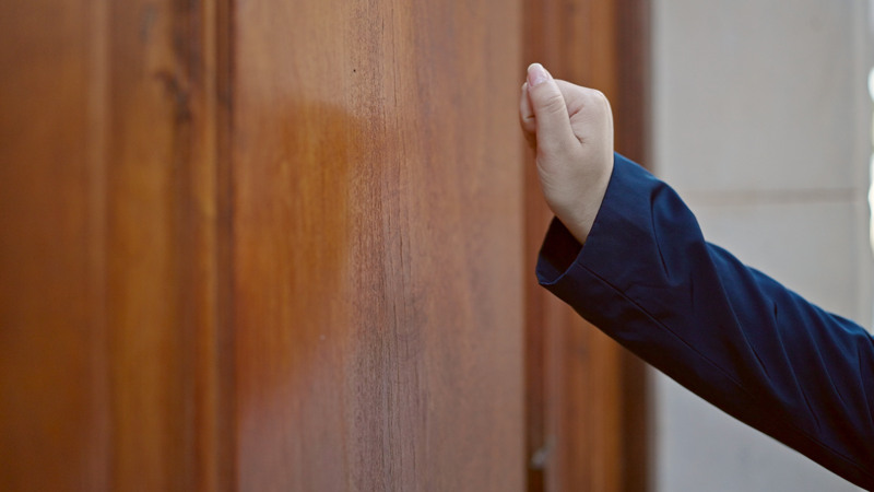 Kvinna knackar på en trädörr.