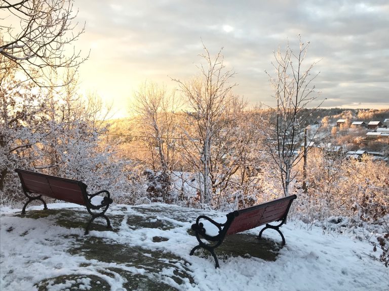 Några bänkar som sitter på toppen av en snötäckt sluttning.