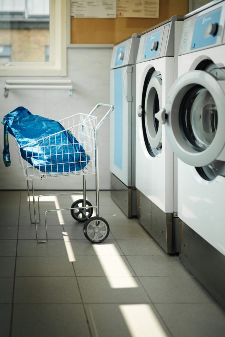 En kundvagn som står bredvid en tvättmaskin.
