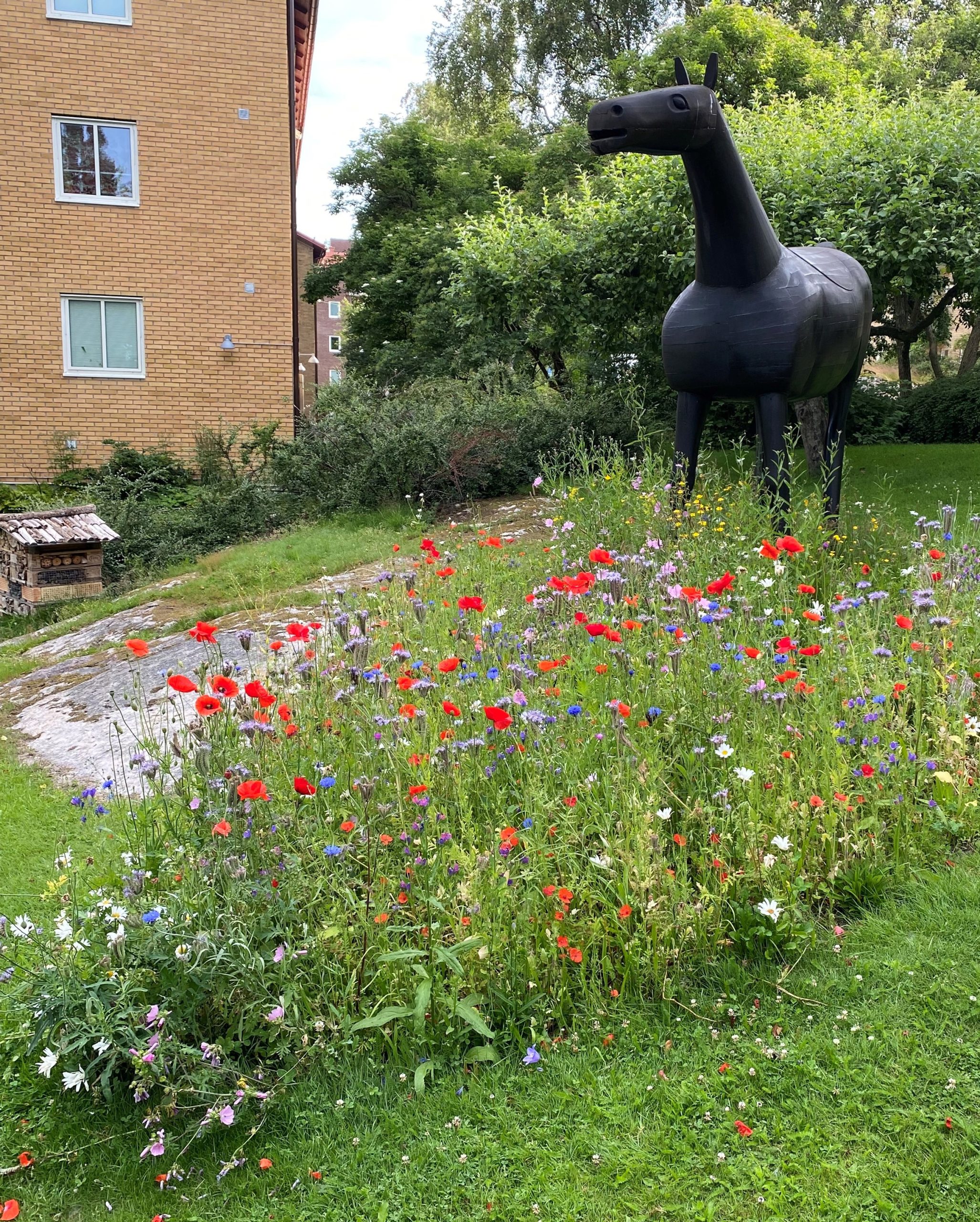 En staty av en häst i ett blomsterfält.