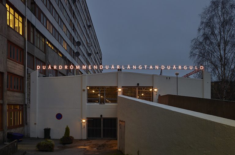 En stor byggnad med en skylt där det står "Du är drömmen, du är längtan, du är guld".