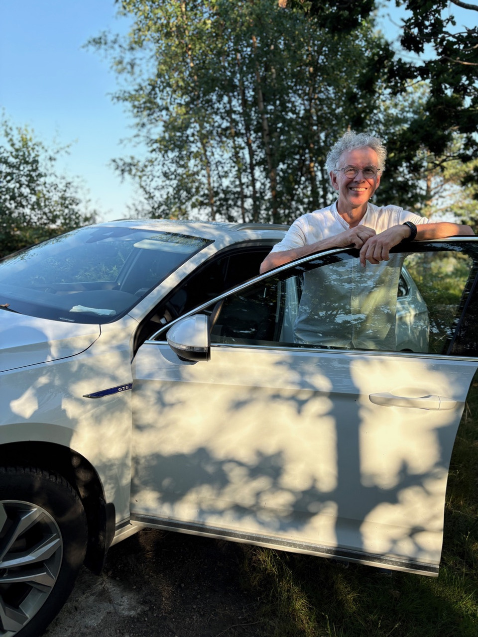 Bostadsbolagets hyresgäst Bo som lutar mot en bildörr och ler mot kameran.