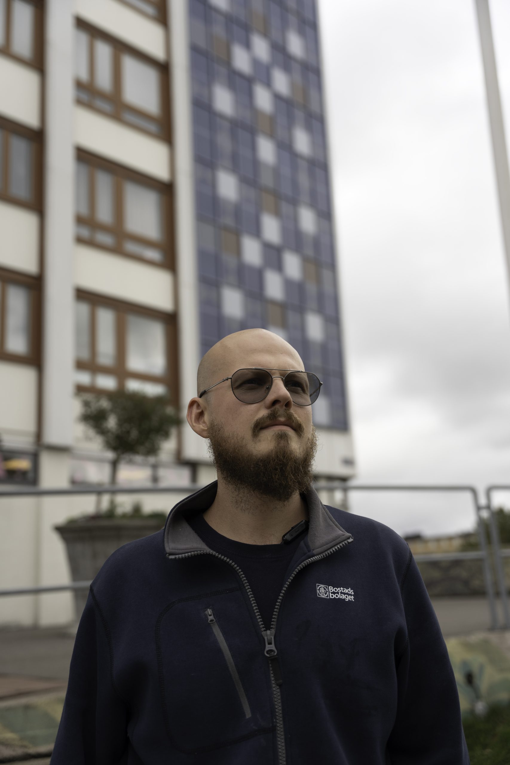 Bostadsbolagets fastighetsvärd Johan står framför Skivhuset i Biskopsgården med glasögon på.