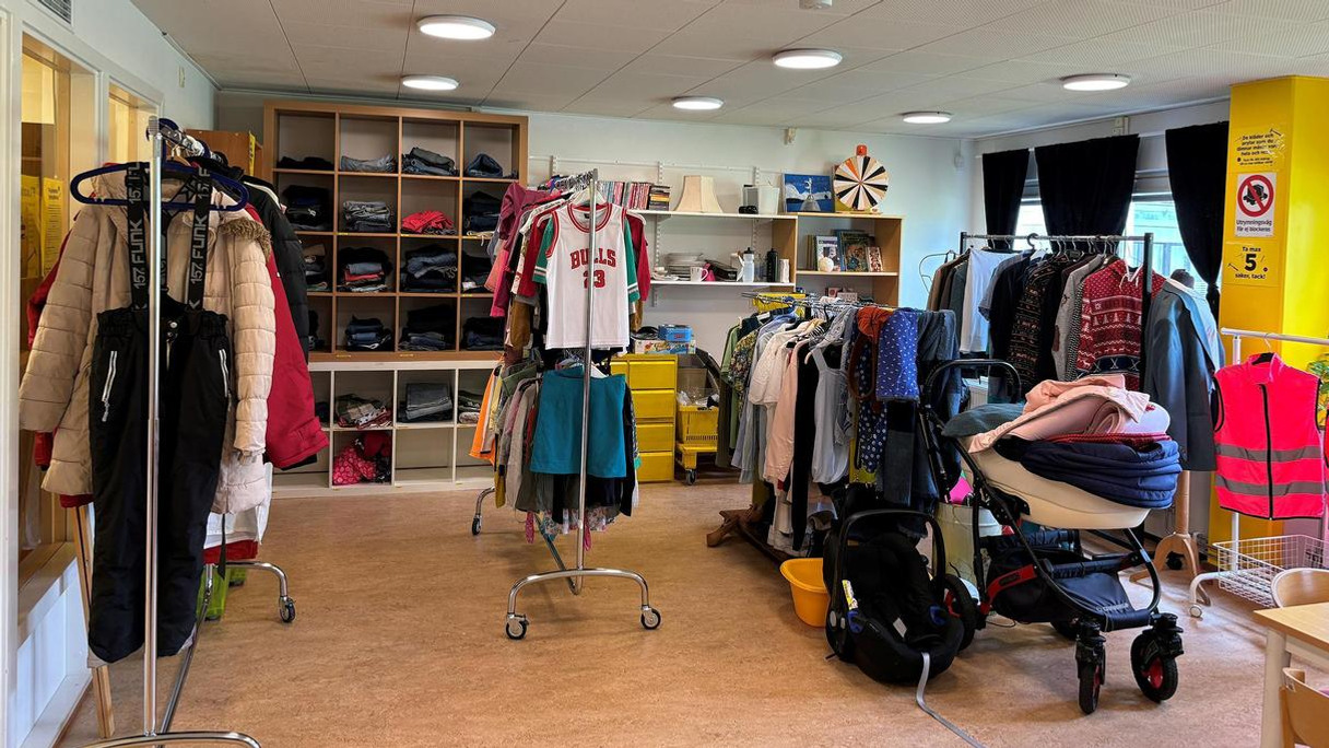 Ett rum fyllt med massor av kläder och en barnvagn.