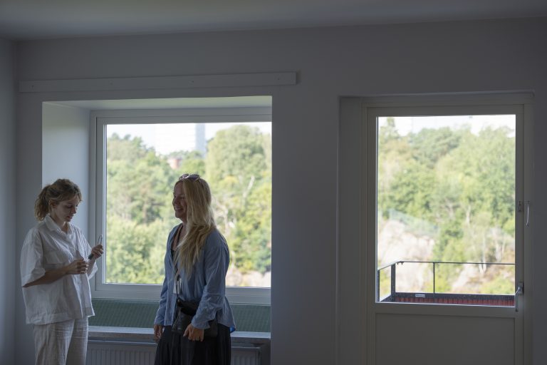 Ellen och Sandra från Bostadsbolaget står och skrattar i en nyrenoverad lägenhet på Kalendervägen i Kortedala. 