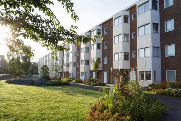 Ett hyreshus med en grön gräsmatta framför sig.