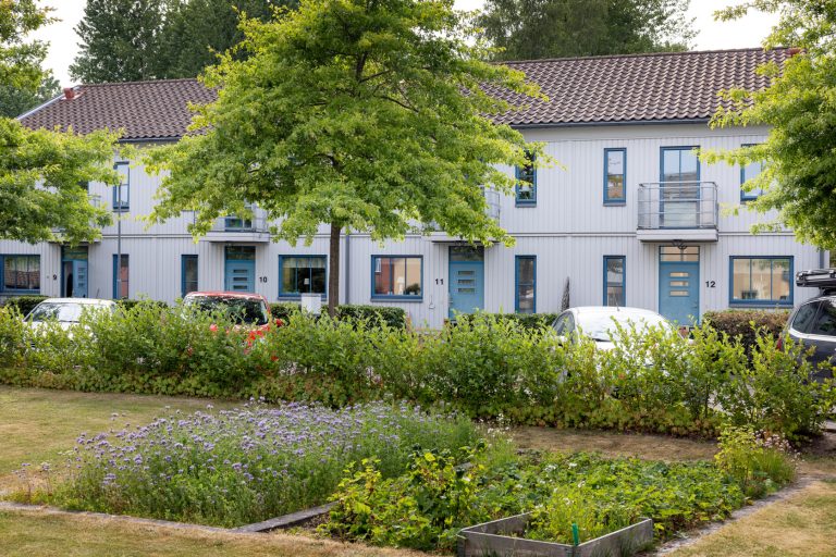 En bil parkerad framför en vit byggnad.