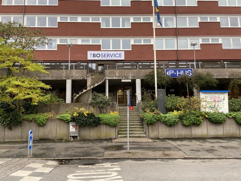 En hög byggnad med en flagga och skylt där det står Boservice.