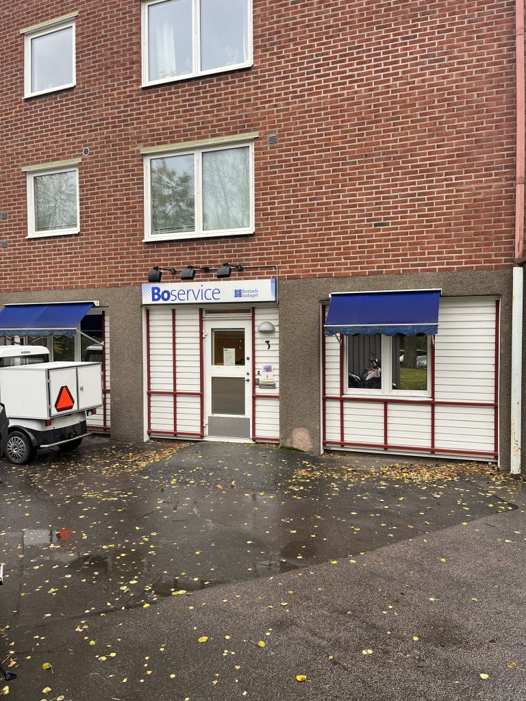 En vit lastbil parkerad framför en byggnad.