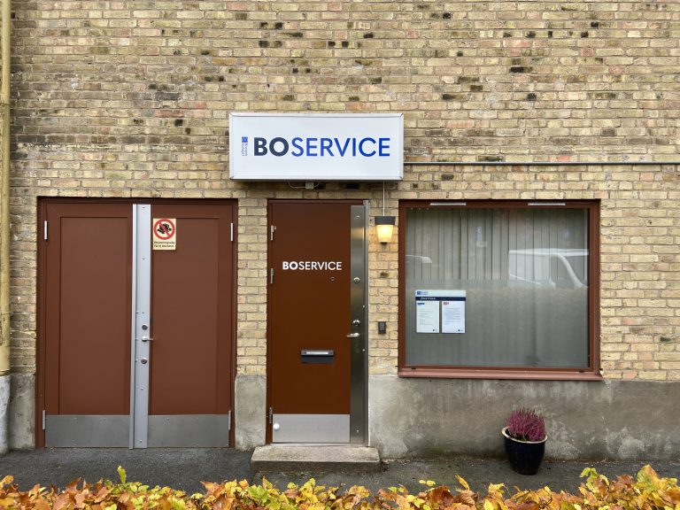 En tegelbyggnad med två dörrar och en skylt på framsidan där det står Boservice. 