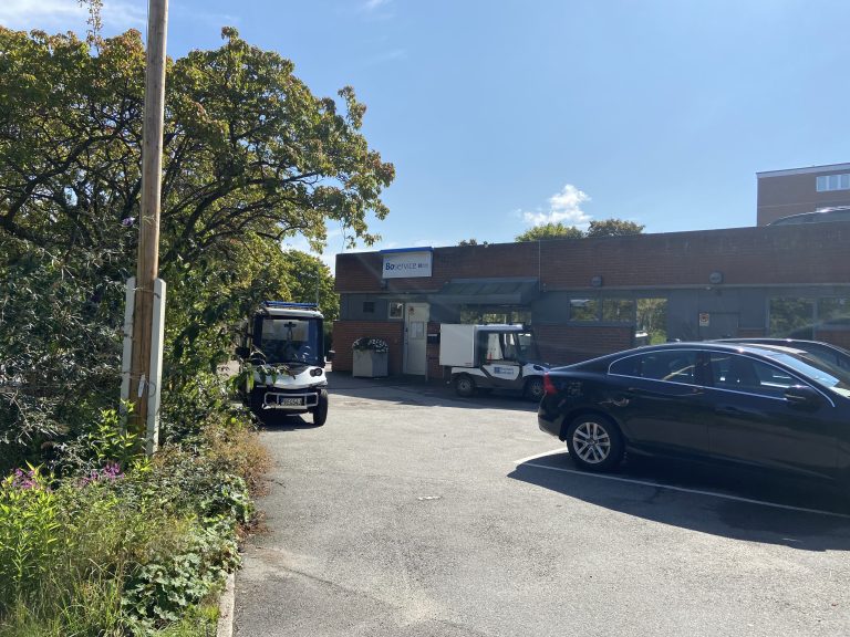 En svart bil parkerad på en parkeringsplats bredvid en byggnad.