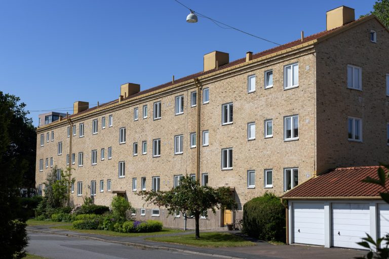 En stor tegelbyggnad med garage på sidan av den.