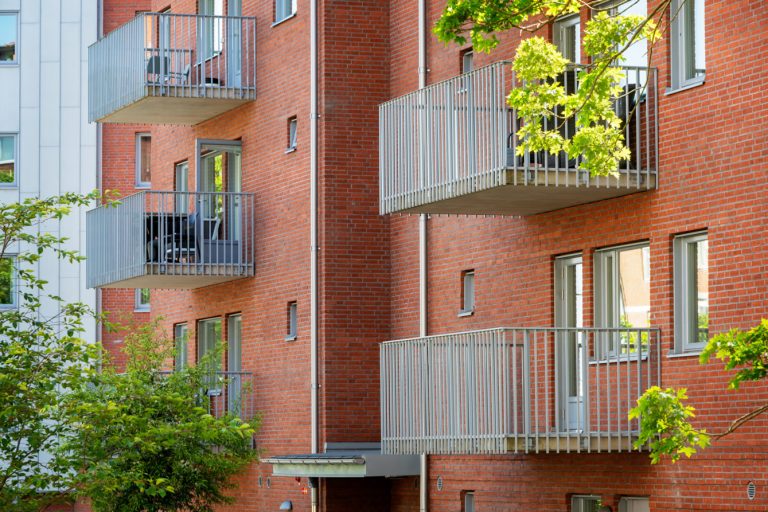 Ett hyreshus i rött tegel med balkonger och balkonger.