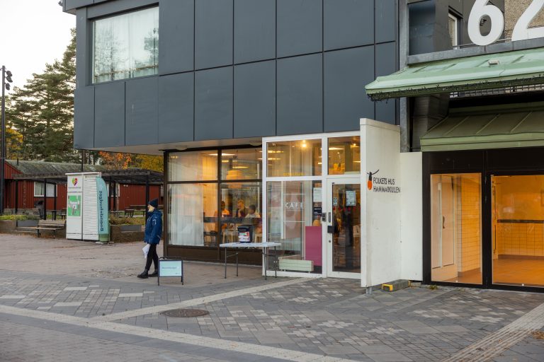 En man går förbi en butiksfasad på en gata i en stad.