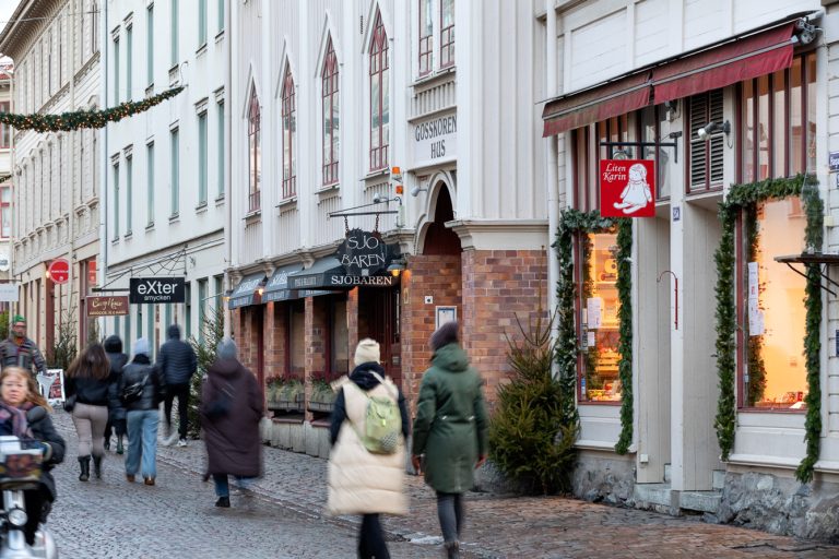 En grupp människor som går längs en gata bredvid höga byggnader.