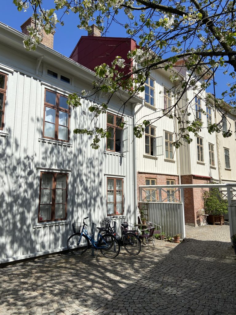 En rad cyklar parkerade bredvid en vit byggnad.