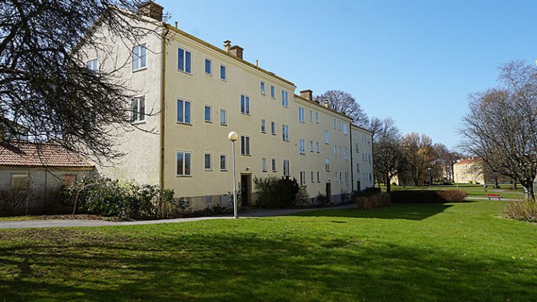 Ett hyreshus med en grön gräsmatta framför sig.