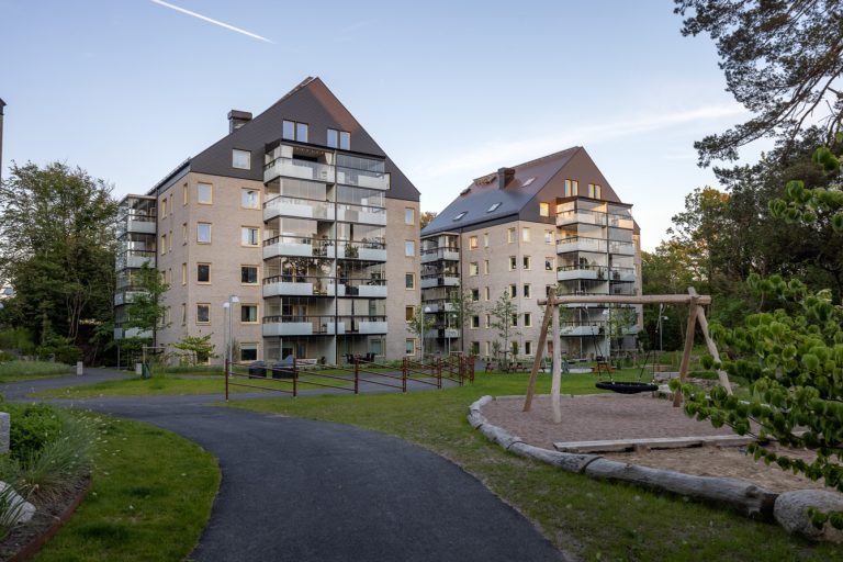 Ett hyreshus med en lekplats framför sig.