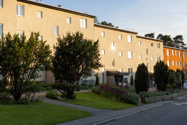 En stor byggnad med många fönster intill en gata.