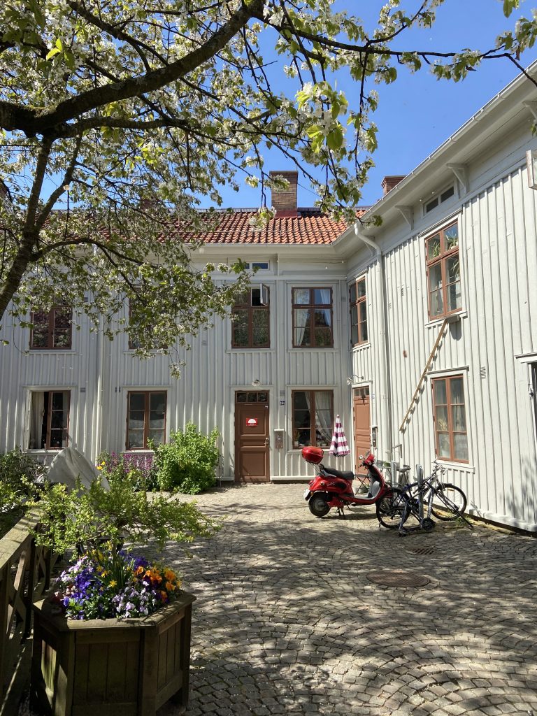 En röd moped parkerad framför en vit byggnad.