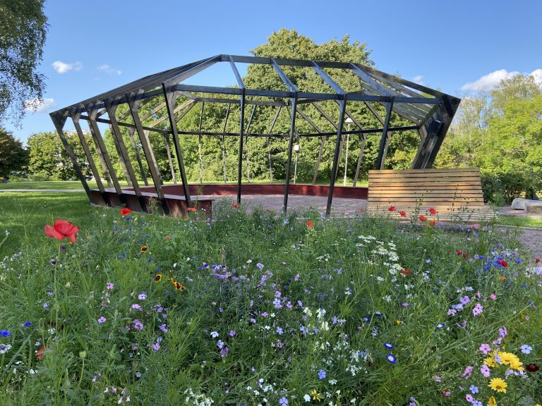 En stor juvel av trä omgivet av vildblommor i en park.