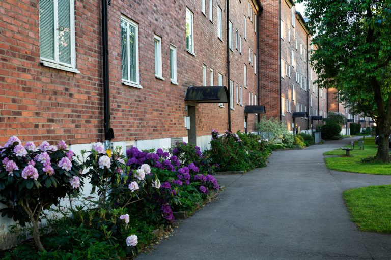 En tegelbyggnad med många fönster och blommor framför.