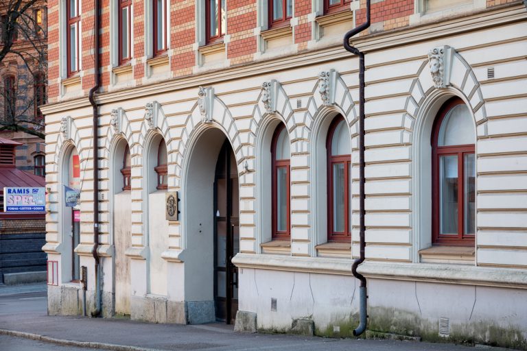En gammal byggnad med välvda fönster i ett gathörn.
