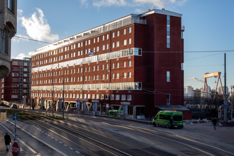 En röd tegelbyggnad som ligger bredvid ett spår för spårvagn.