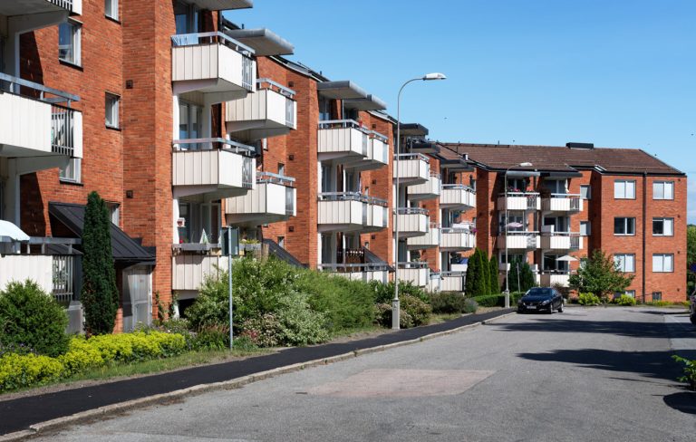 En rad flerfamiljshus i tegel med balkonger.