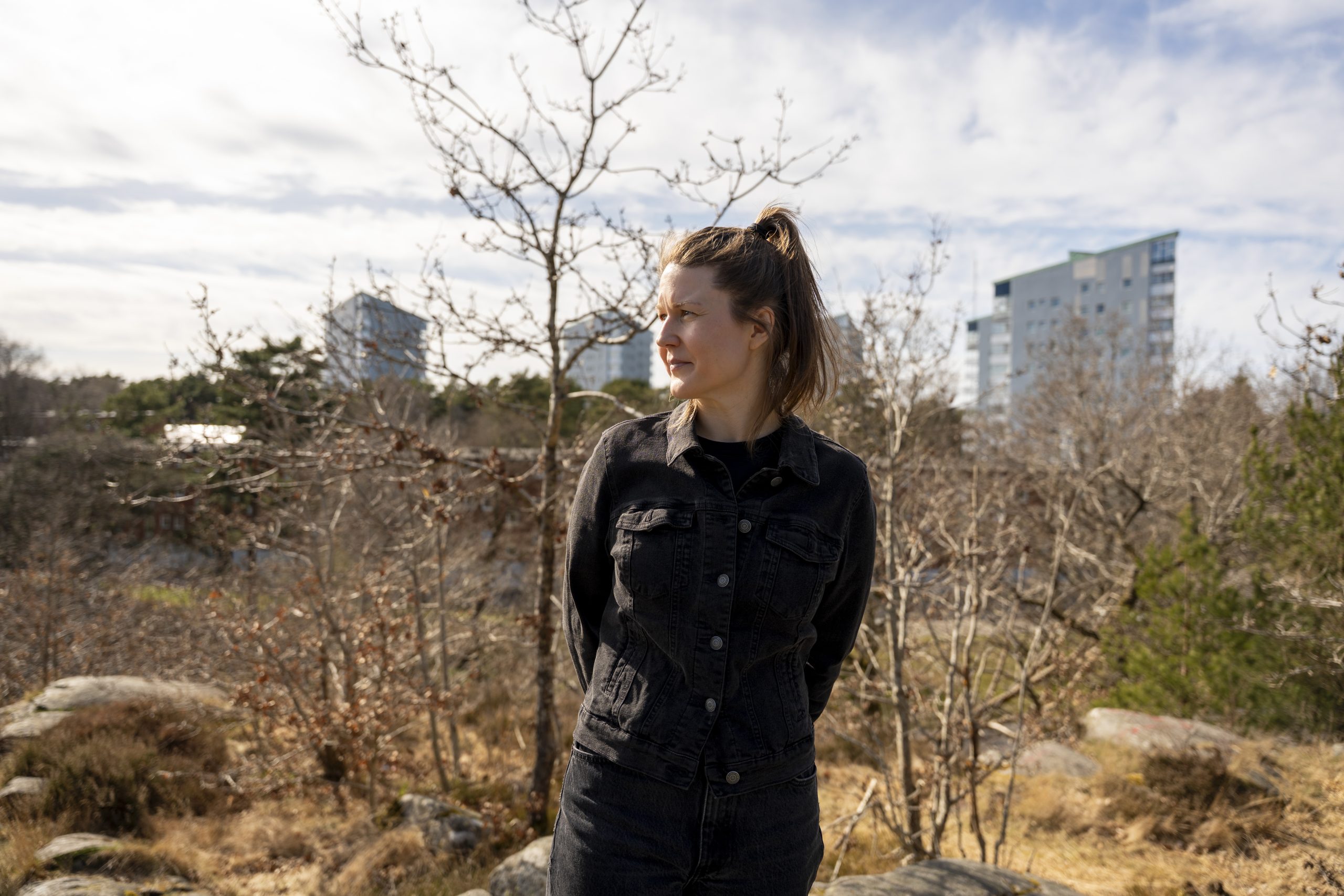 Konstnären Dominika på berget i Kortedala. I bakgrunden syns en kal, solig natur och lägenhetsbyggnader.