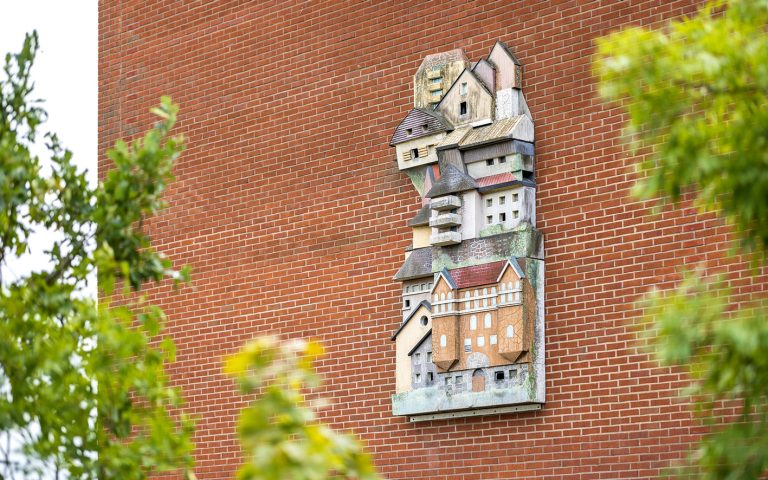 En byggnad med ett konstverk av små trähus på sidan.